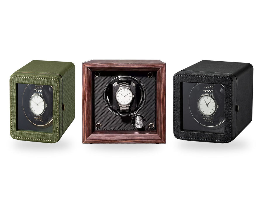 The gifts winders side by side on a white background, plain unbranded watches on the cushions.